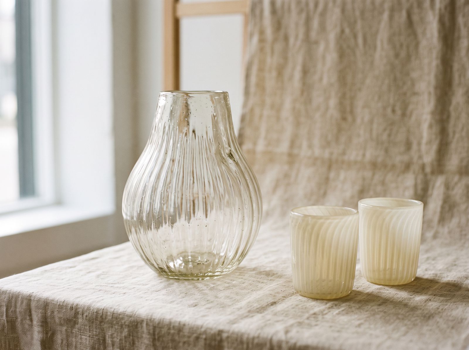 Ribbed clear vessel with two ivory tumblers