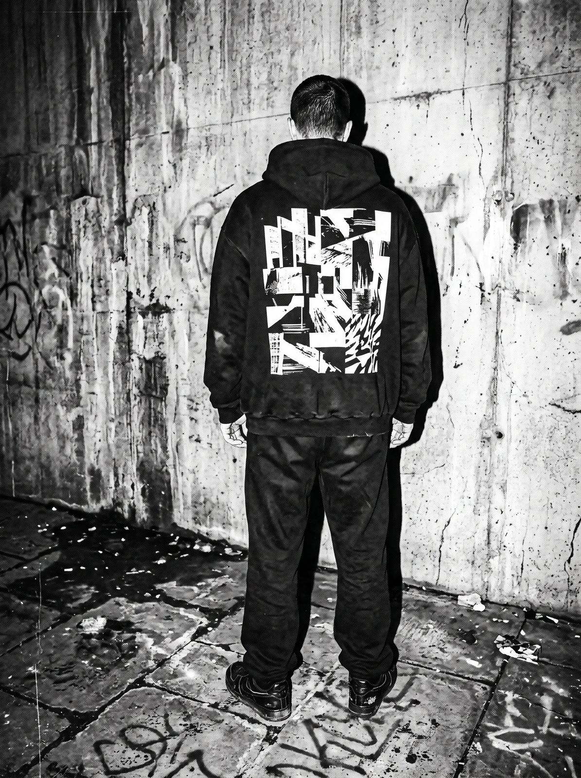 Model from behind, large graphic across the hoodie back, concrete wall