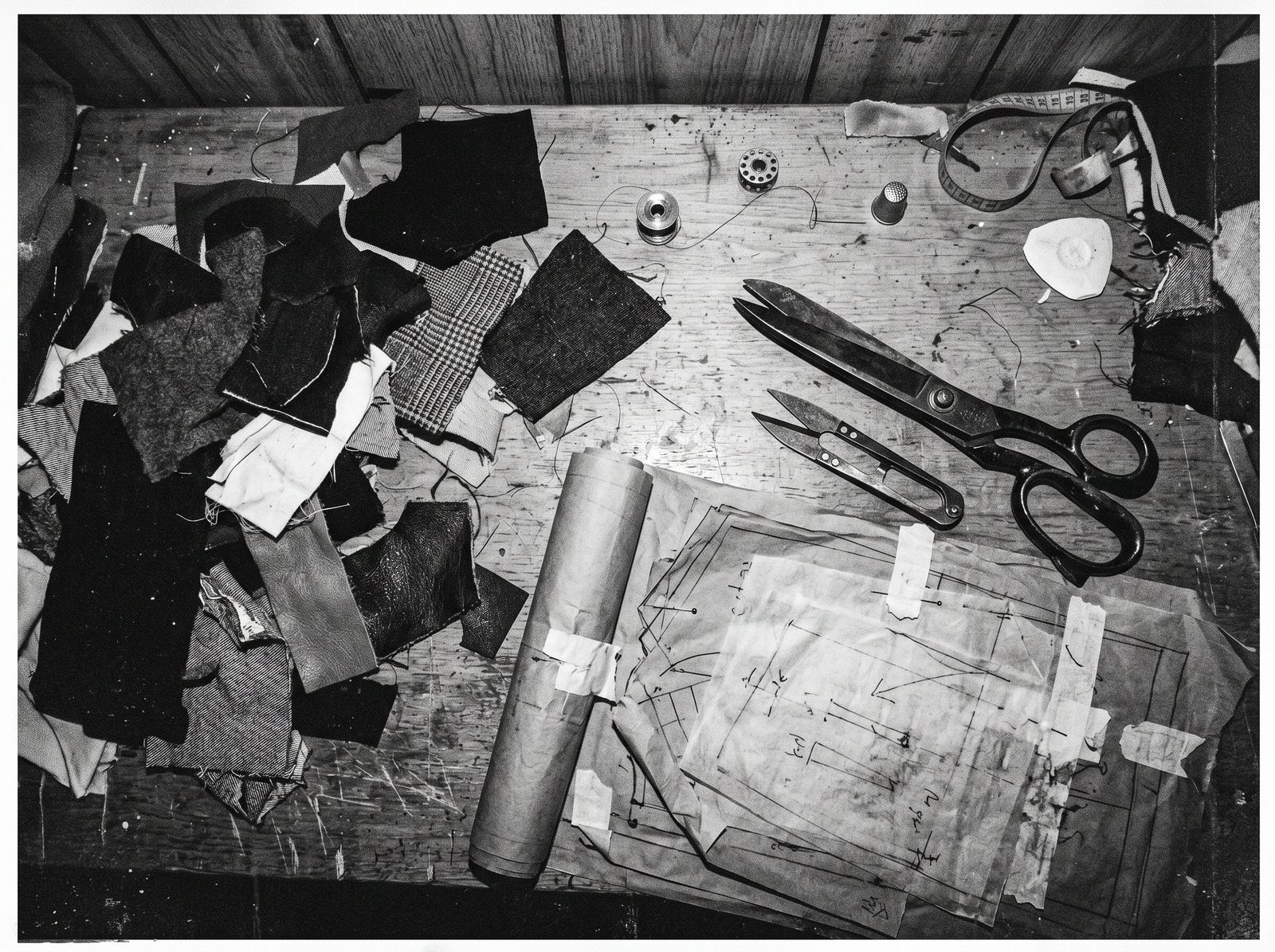 Tailor cutting table with fabric scraps, scissors and pattern paper